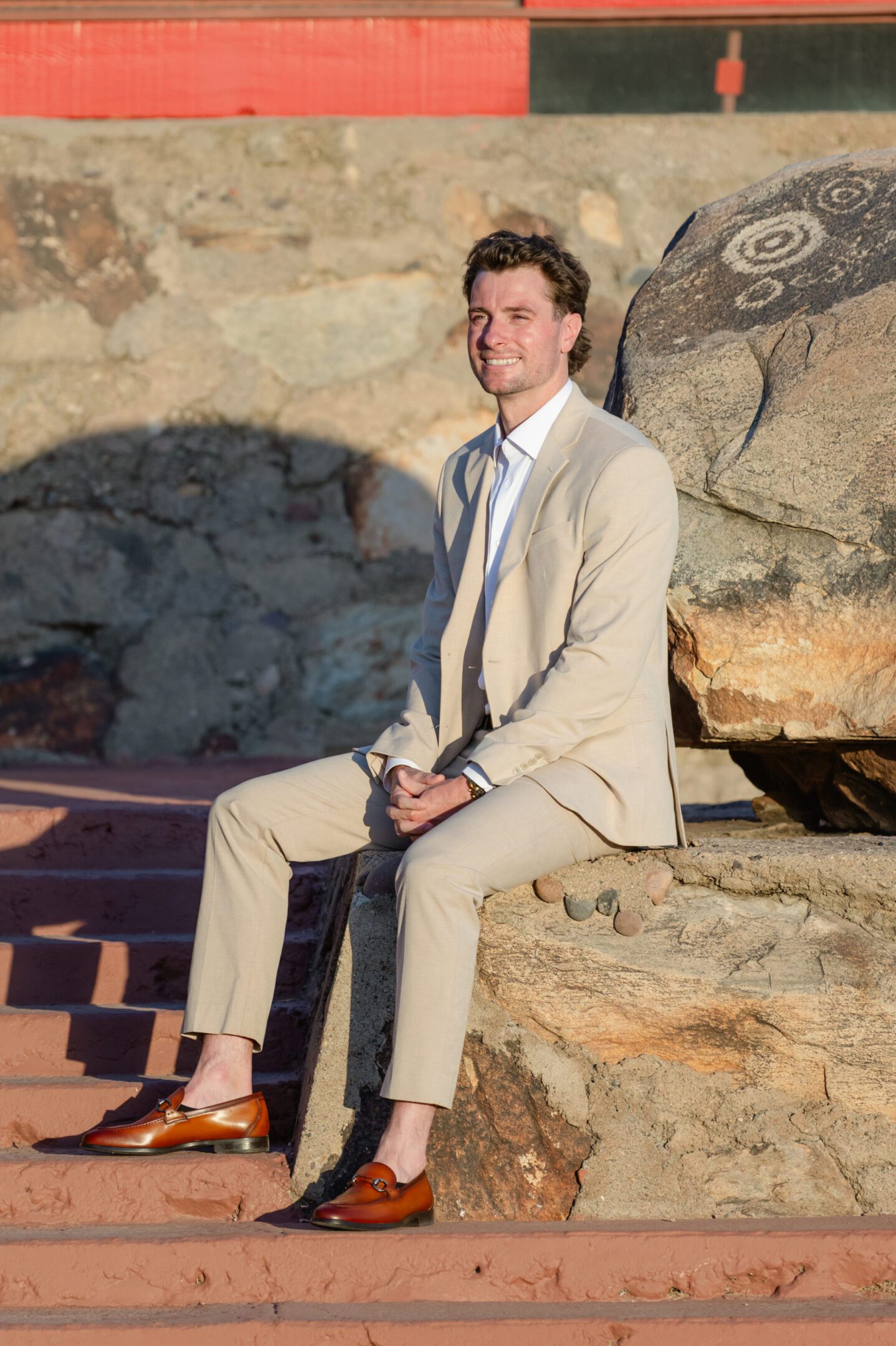 Man in beige suit sitting on rock steps