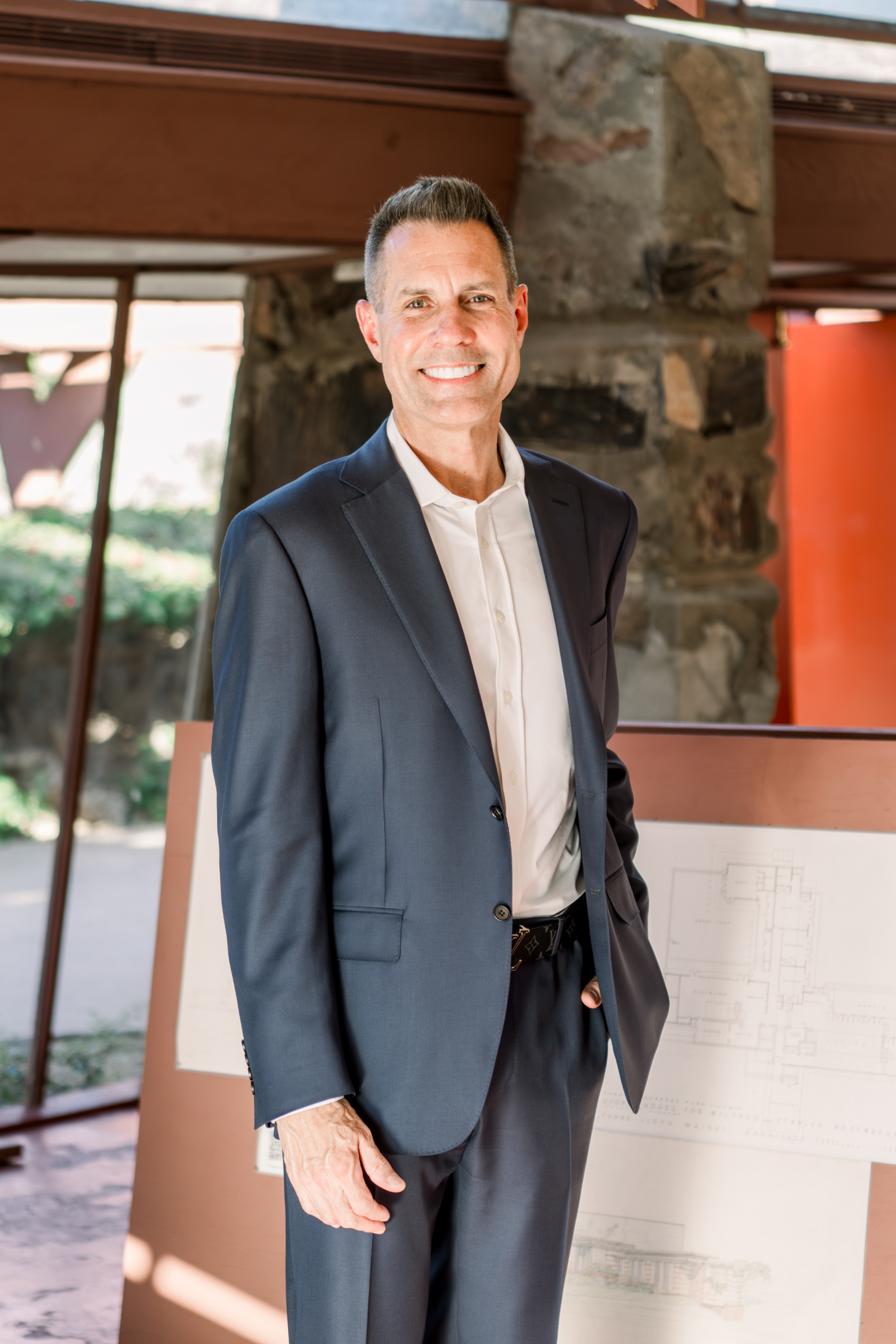 Smiling businessman in suit near architectural plans