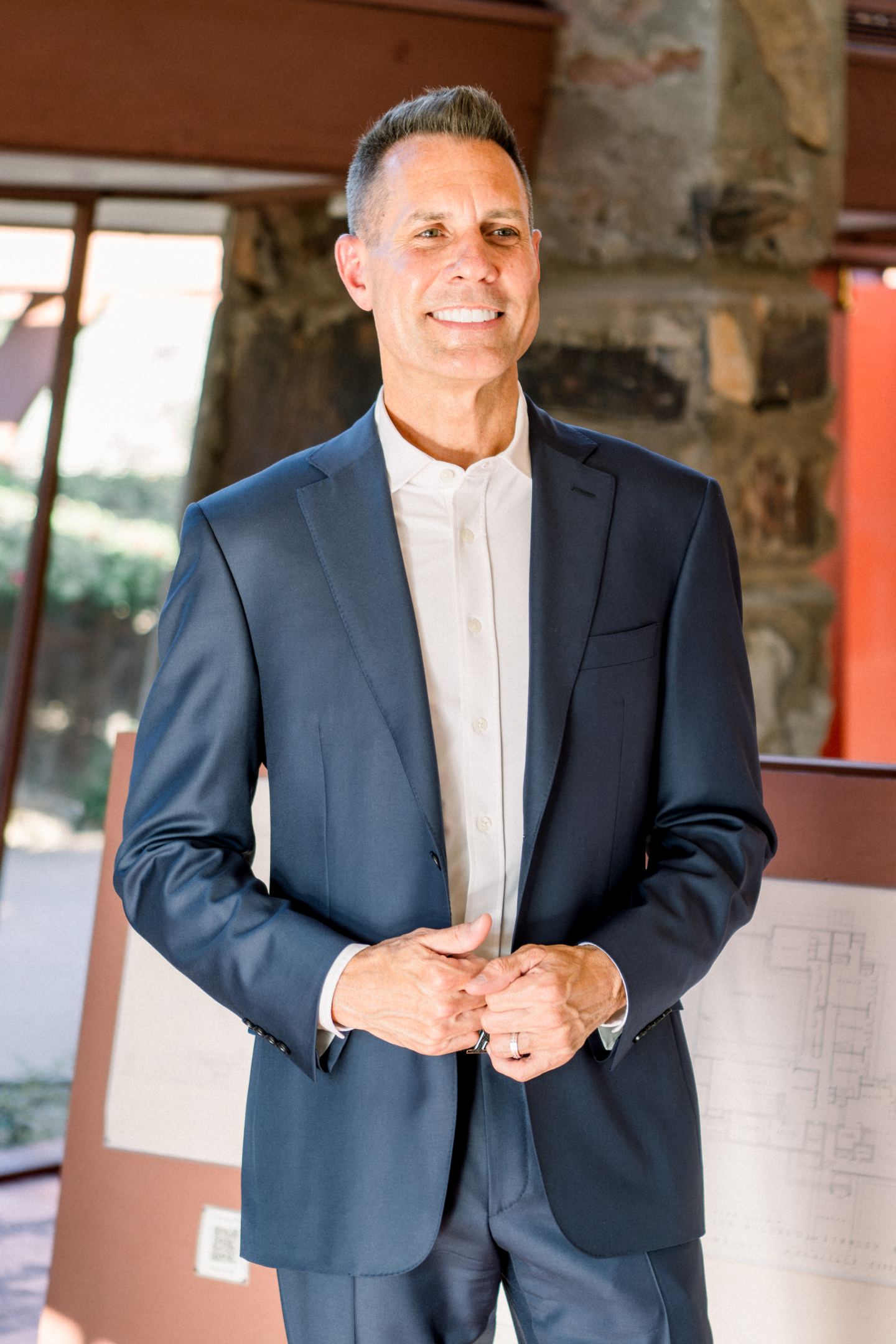 Smiling man in navy suit at architectural plans