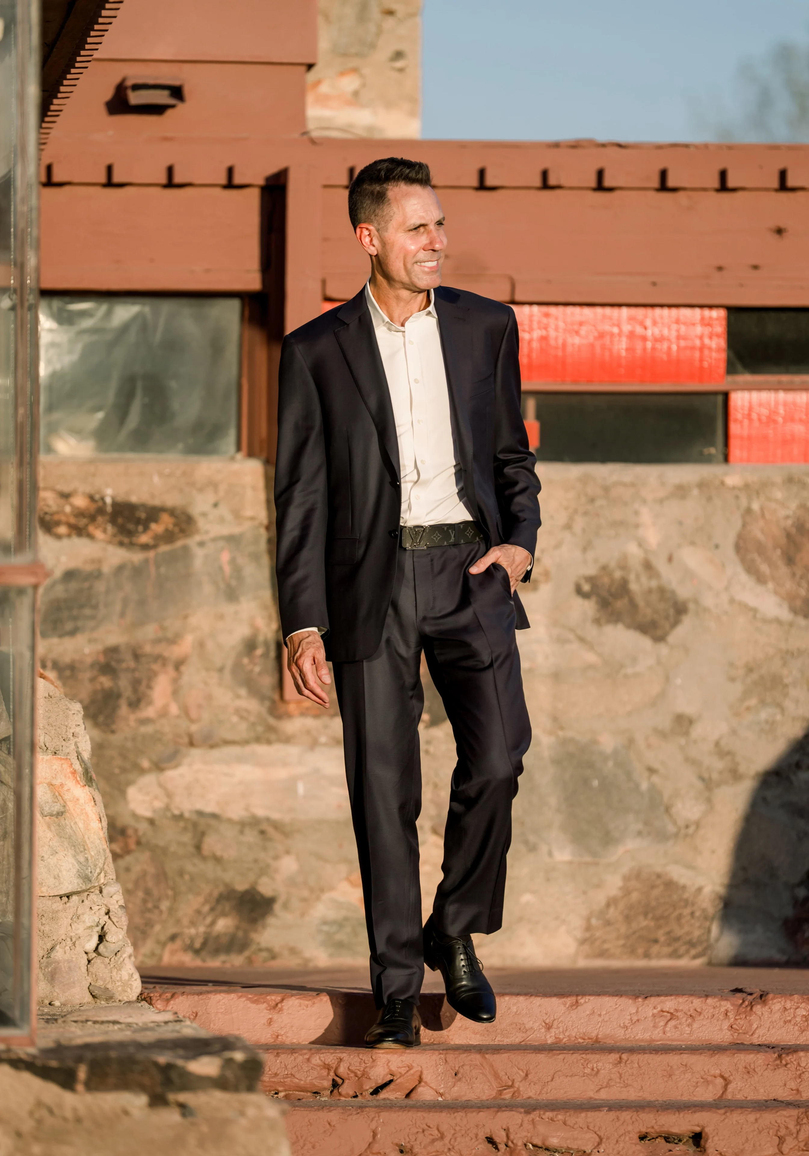 Smiling man in dark suit walking outdoors