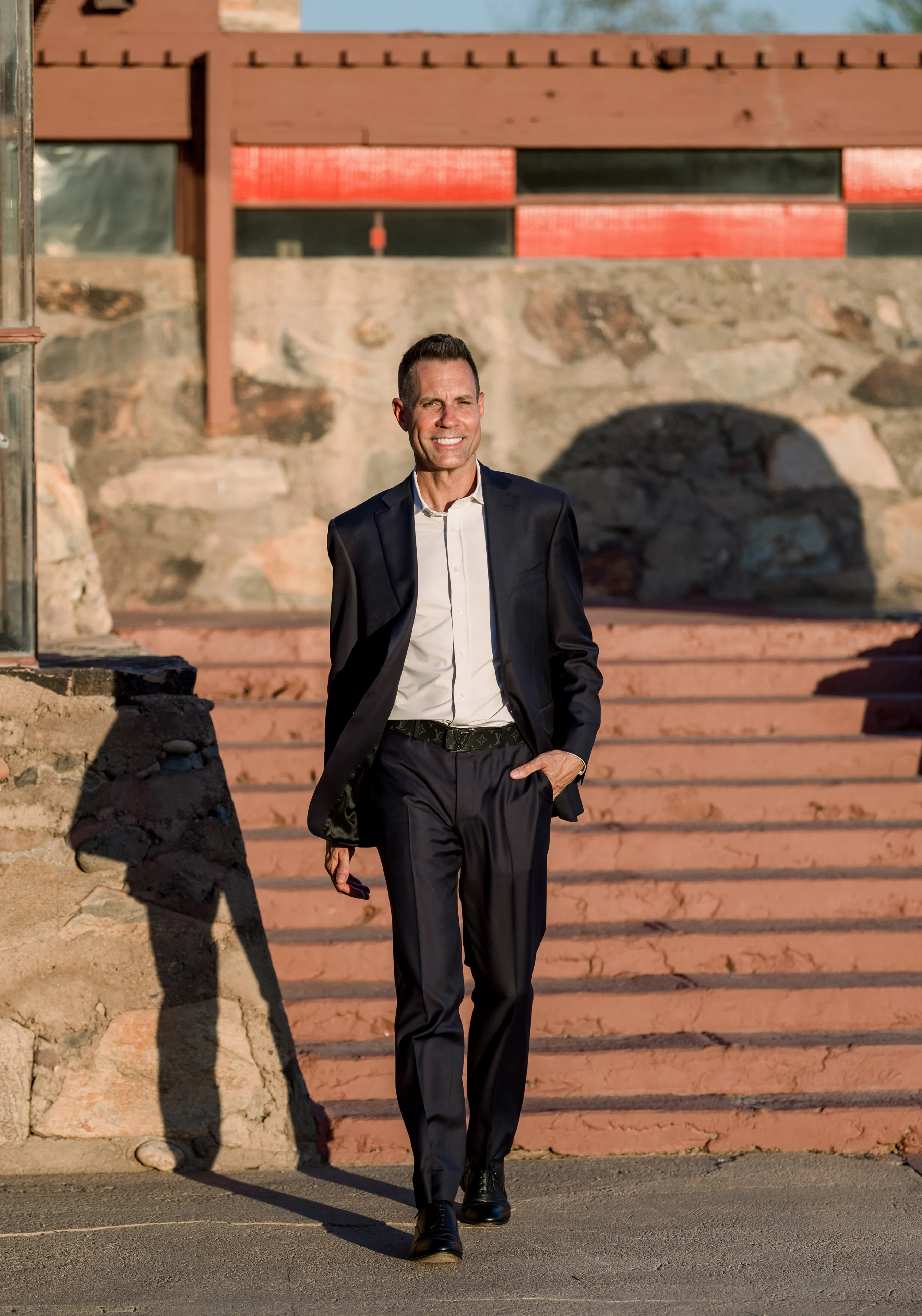 Smiling man in suit walking by stone steps