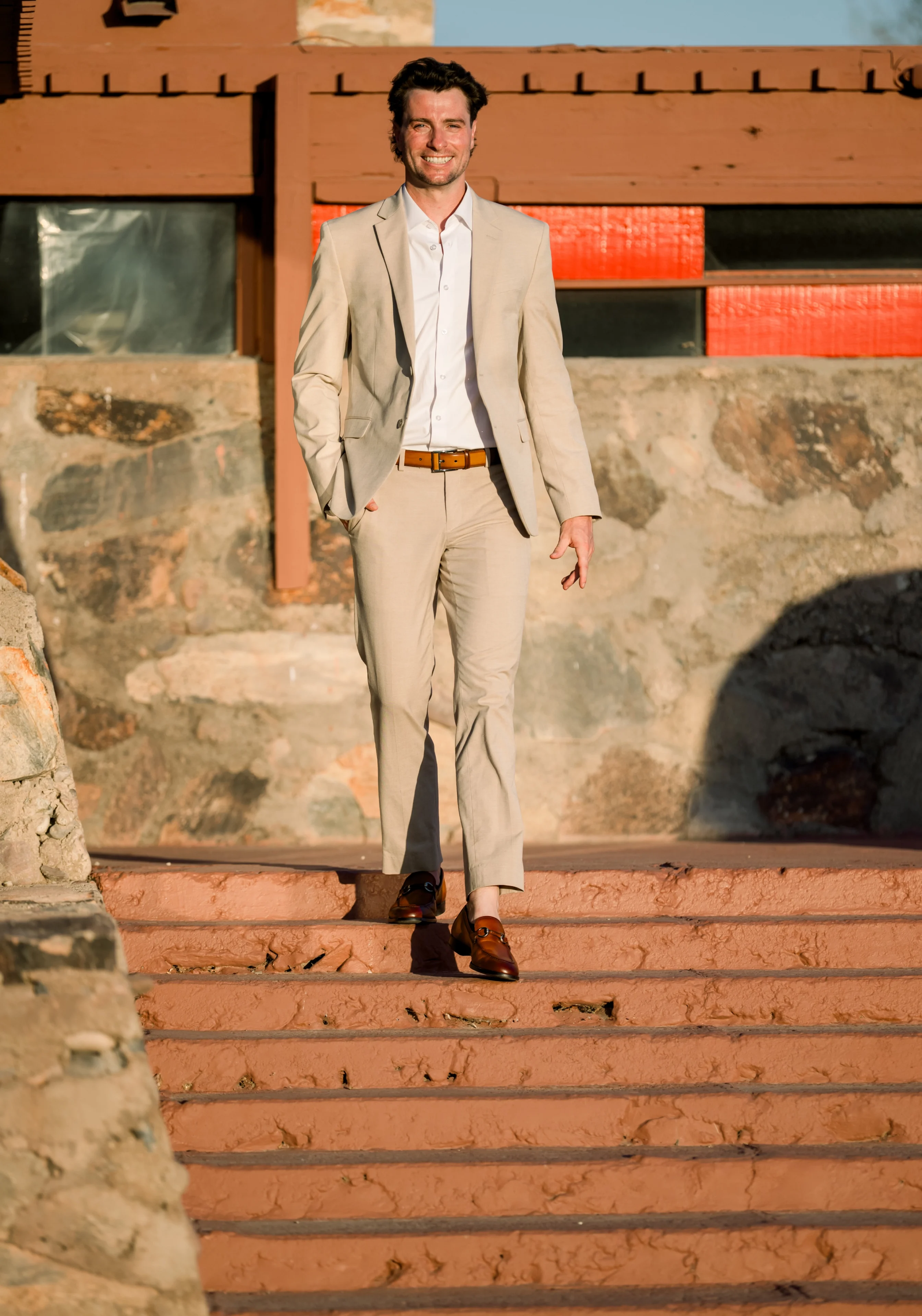 Smiling man in beige suit walking down stairs