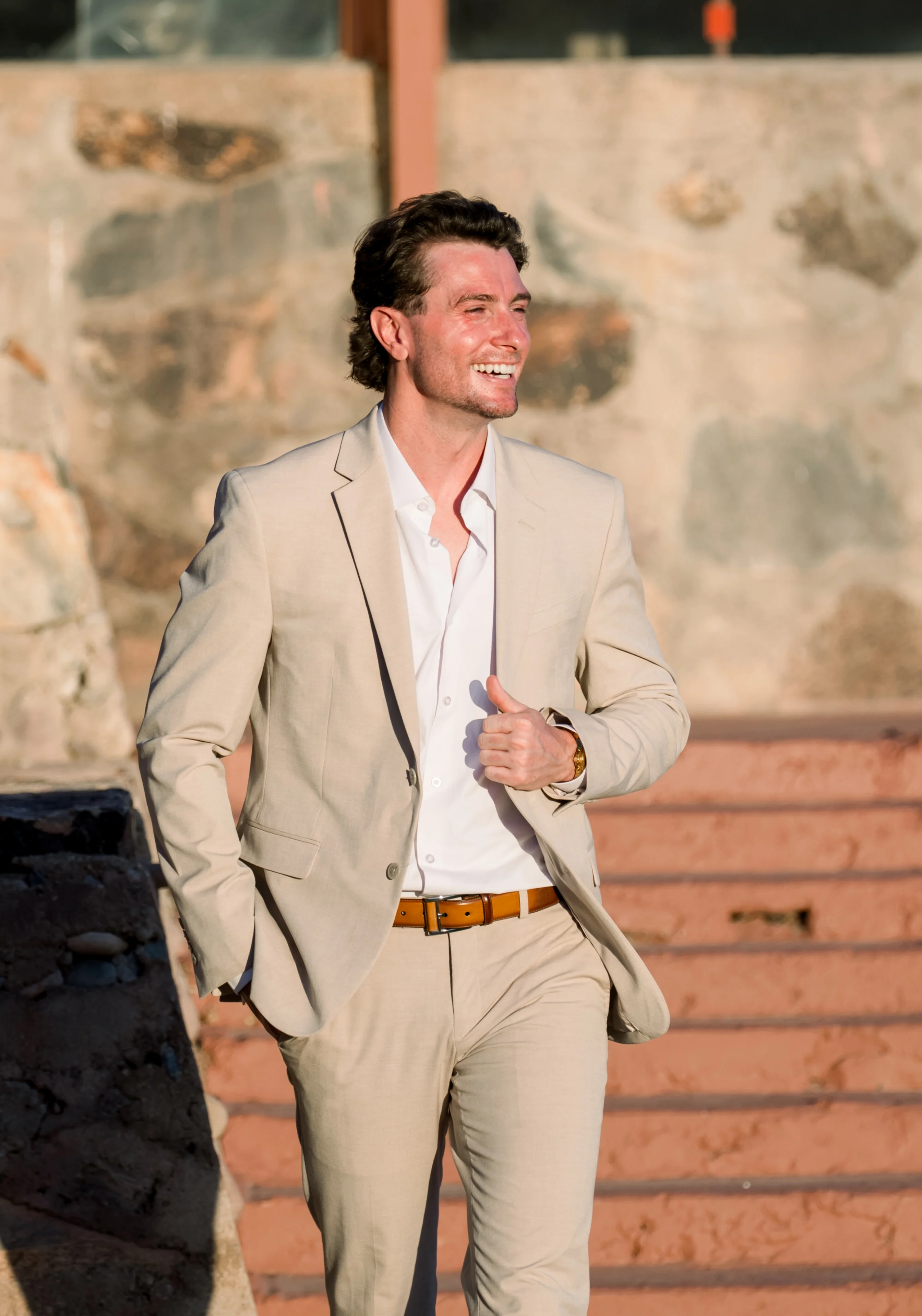 Smiling man in beige suit walking down steps