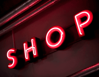 Red neon shop sign angled on dark wall