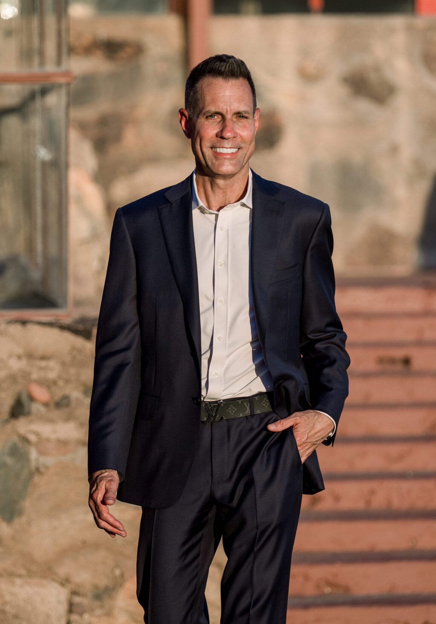 Man in navy suit smiling outdoors