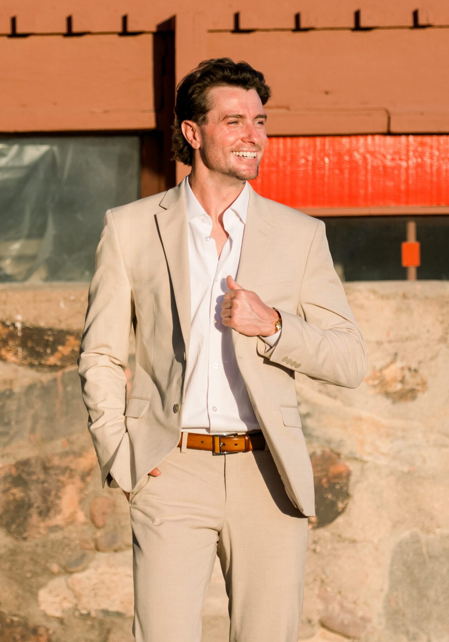 Smiling man in sunlit beige suit outdoors